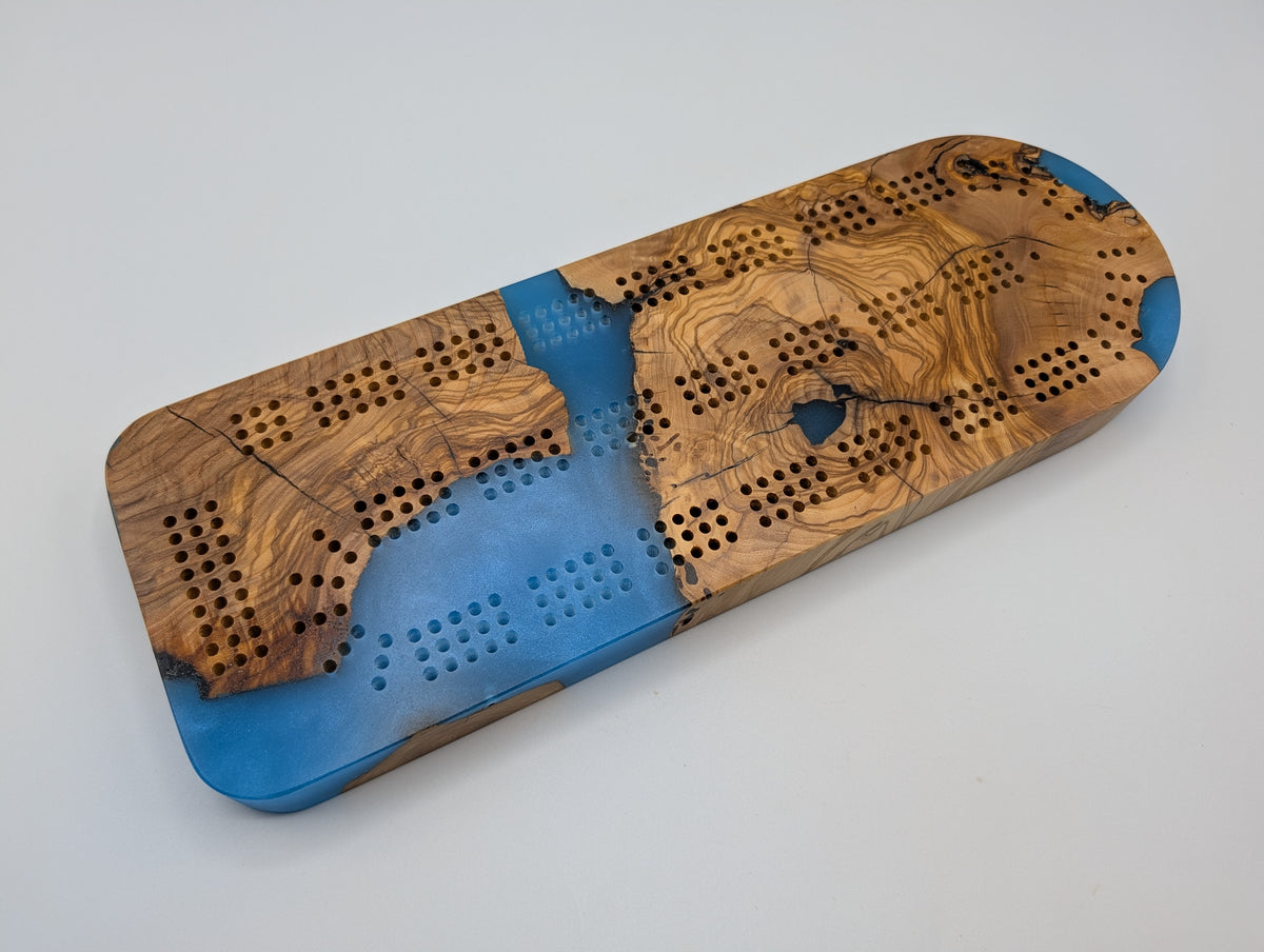 Azure Cove Origin Turkish olivewood cribbage board with bright blue resin — playing face.