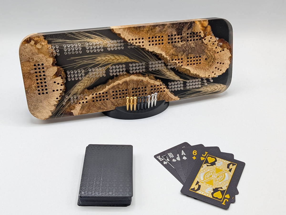 One-of-a-kind Imprint brown mallee burl cribbage board with real Saskatchewan-grown wheat, on its included display stand with pegs and a black playing-card deck.