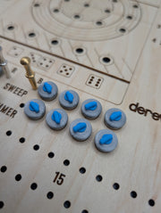 Blue-handled miniature curling stones beside the engraved dice guide and score track