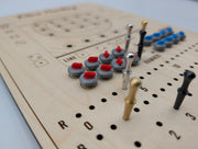 Red curling stones and metal score pegs on Derevo's maple Dice Curling game board