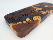 Midnight Islands Origin brasiletta cribbage board with smoky midnight blue resin — close-up of wood, resin and playing tracks.