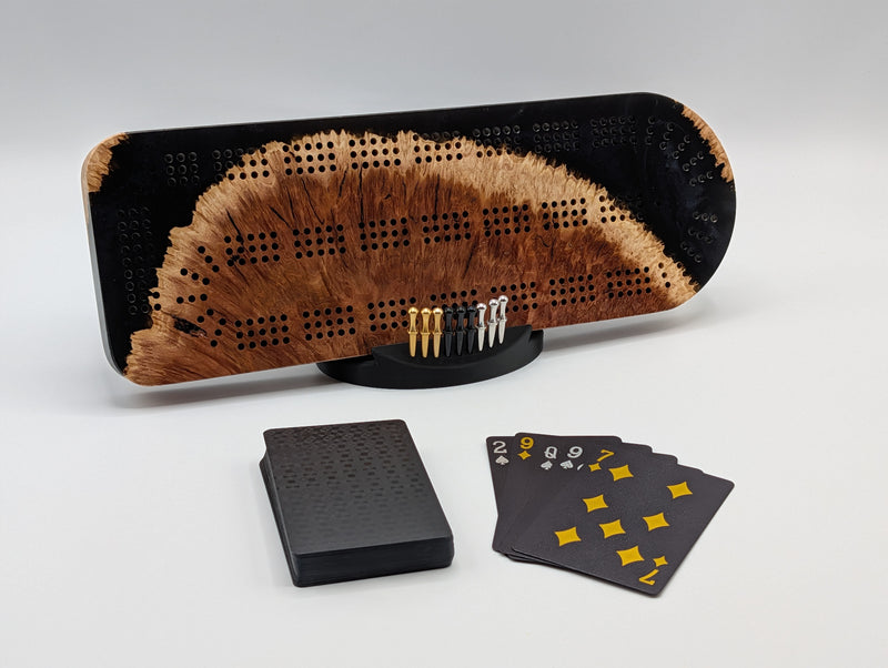 Midnight Shore Origin red mallee burl cribbage board with smoky black resin — shown with included cards, pegs and display stand.
