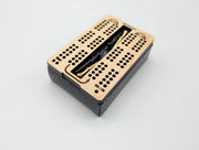 Acorn maple cribbage board with metal pegs in its central storage space