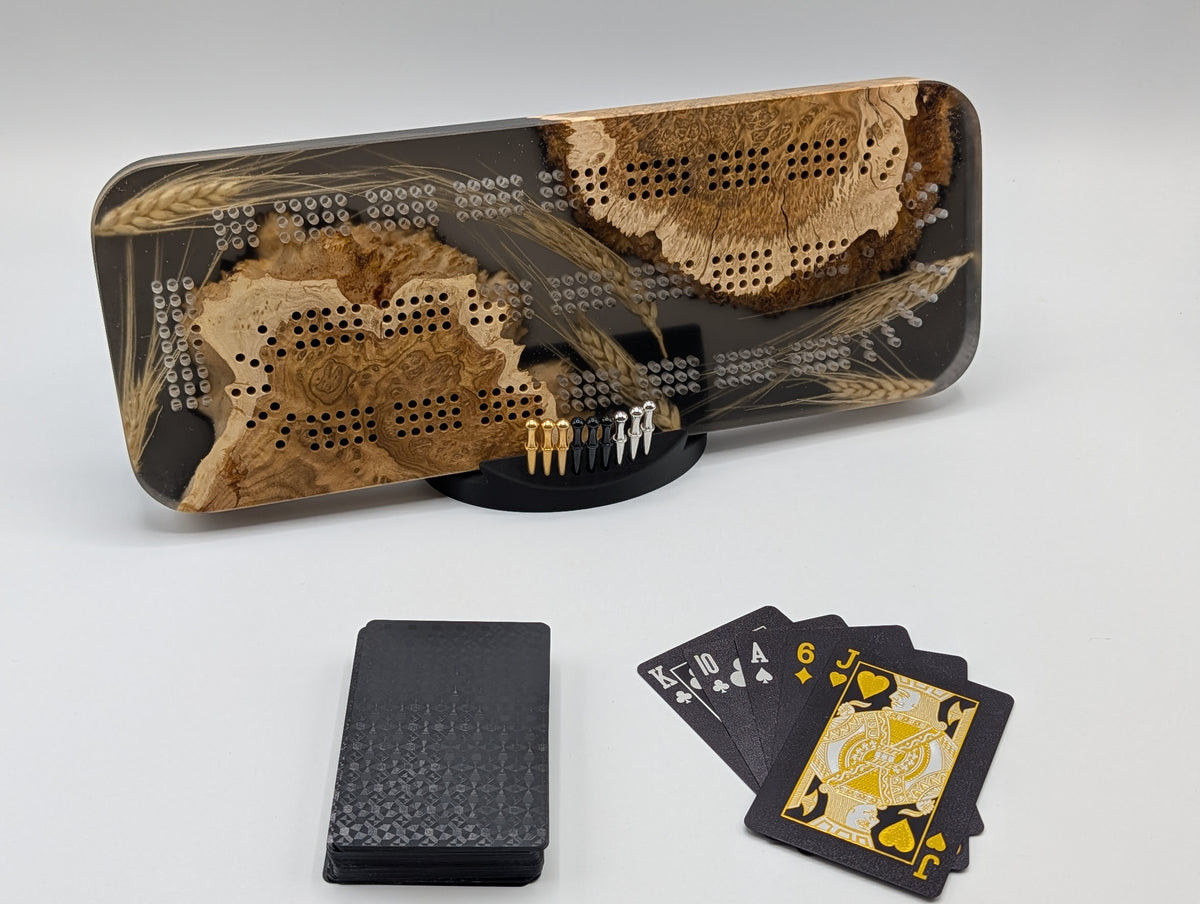 One-of-a-kind Imprint brown mallee burl cribbage board with real Saskatchewan-grown wheat, on its included display stand with pegs and a black playing-card deck.