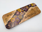 One-of-a-kind Imprint brown mallee burl cribbage board with real strawflowers in yellow, cream and purple, front showing the cribbage tracks and natural burl edges.